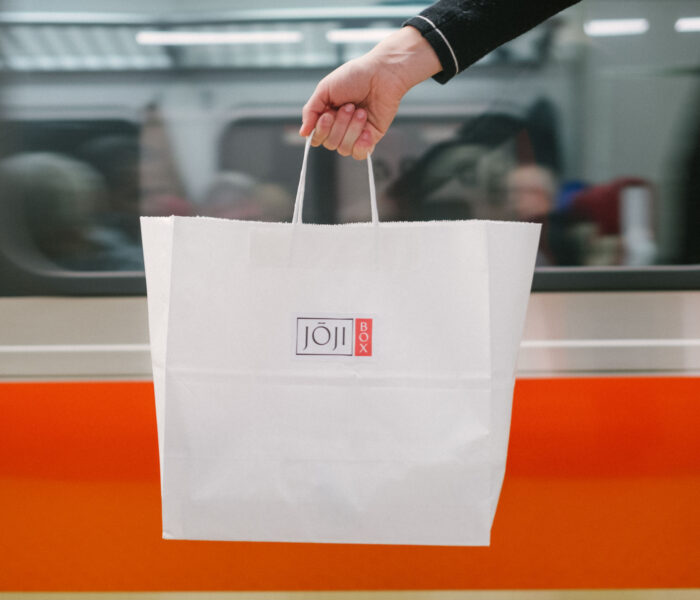 A white Joji Box to go bag in front of a train